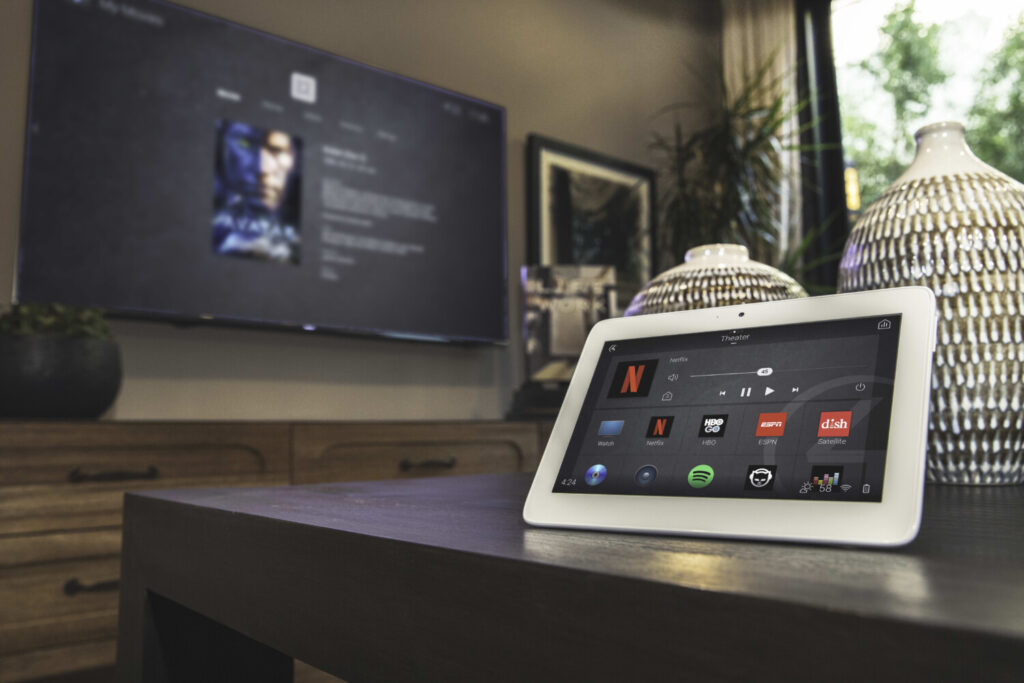 Control4 portable touchscreen in the living room of a West Vancouver home, with a mounted TV in the background