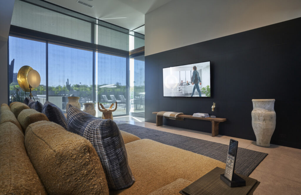 Beautiful media room in Vancouver featuring a Crestron TSR touchscreen remote in the foreground and Crestron motorized blinds lowering to darken the room