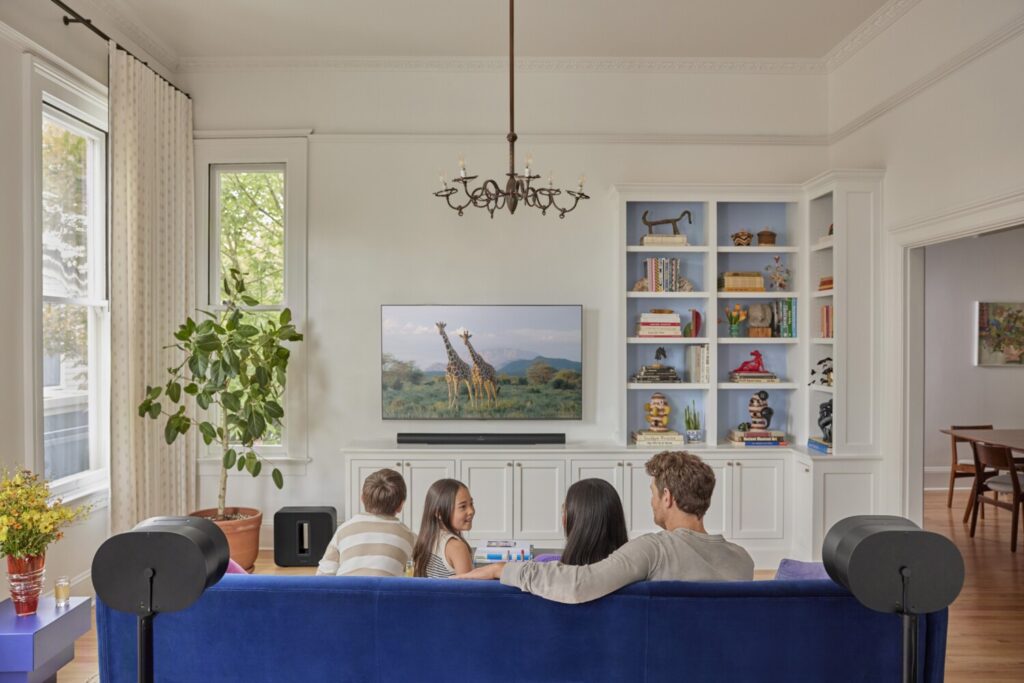 Family enjoying a movie in their family room with a Sonos Arc soundbar installed below the TV for immersive audio