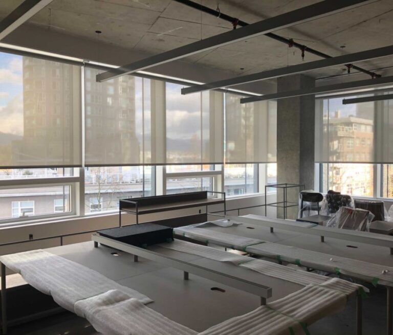 Motorized roller shades across a floor-to-ceiling office window