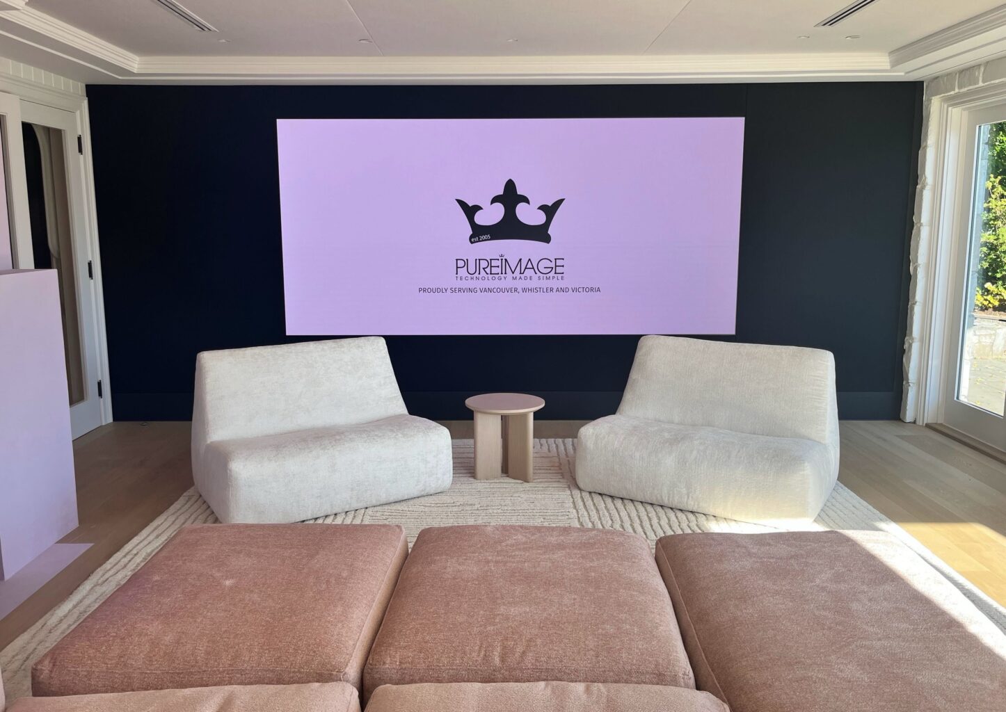 Planar Quantum MicroLED video wall installed flush into a navy feature wall in a private residence, displaying the Pure Image logo above low cream and blush seating