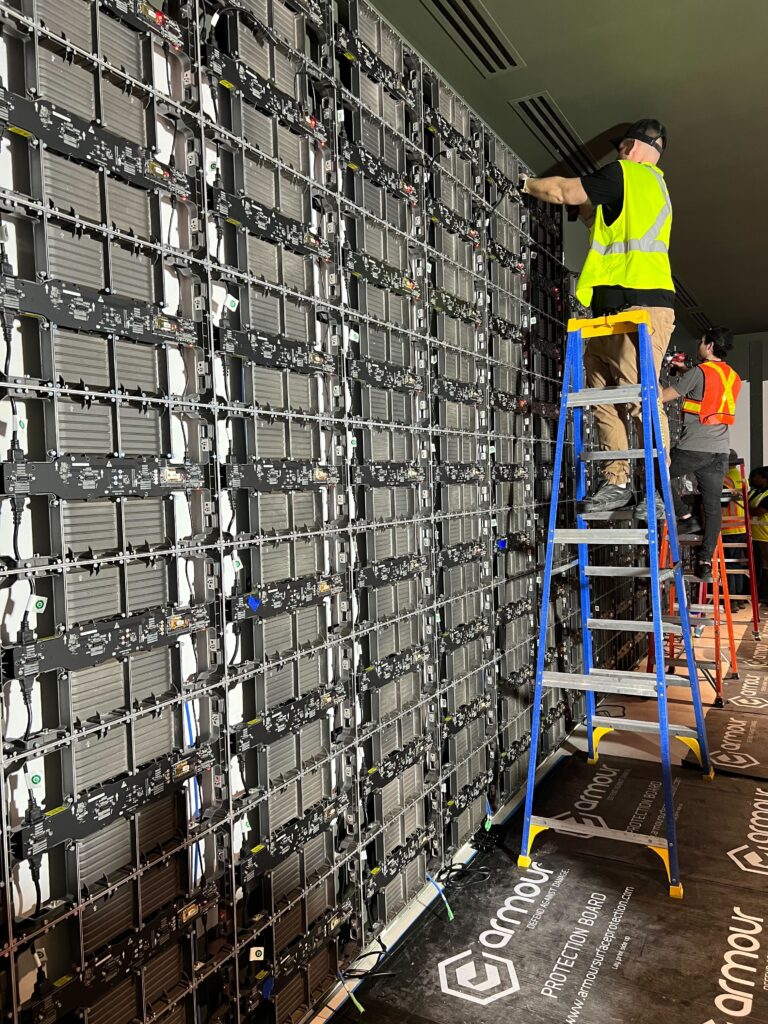 Pure Image technician installing LED video wall panels in Vancouver, demonstrating professional precision and large-scale display assembly.