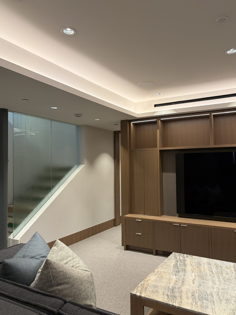 Custom media room in luxury Whistler home featuring Lutron cove and recessed lighting, Sonance in-ceiling speakers and integrated TV wall unit — Pure Image home automation and lighting control Whistler