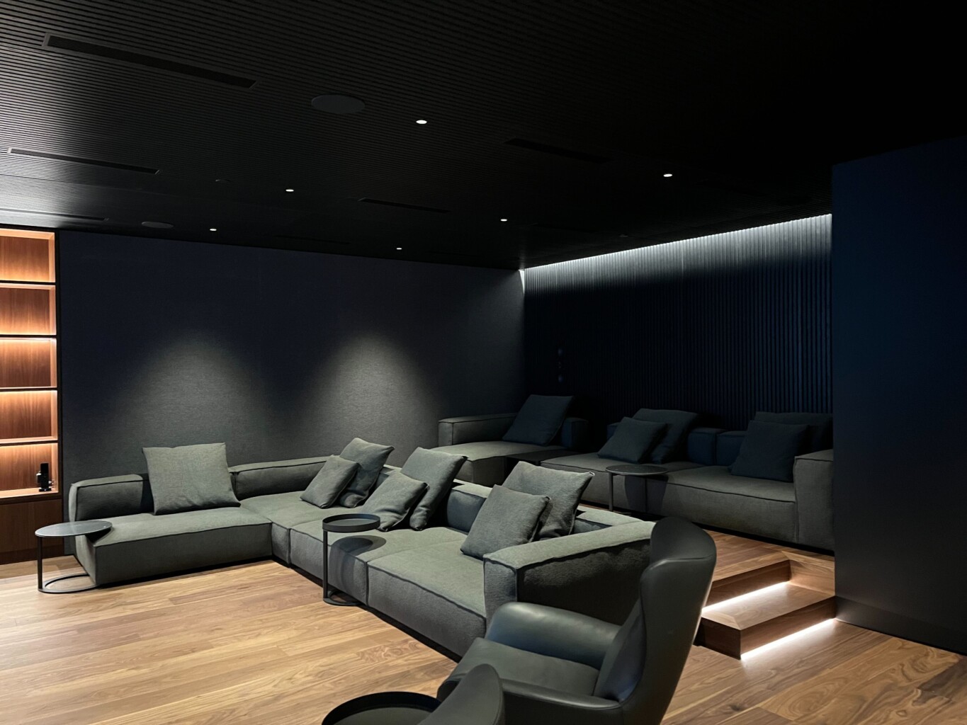Custom home theatre with tiered sofa seating, LED step lighting, and acoustic wall panels, designed and installed by Pure Image.