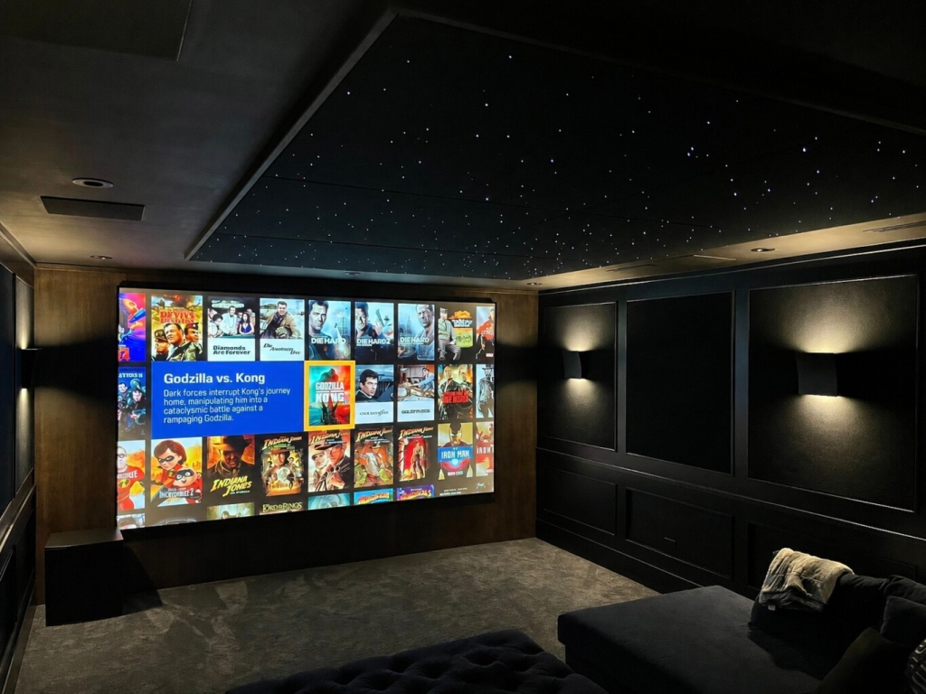 Custom luxury home theatre with fibre optic star ceiling, large format projection screen, Kaleidescape movie server and ambient wall lighting — home theatre installation by Pure Image Vancouver, Victoria, Whistler and Calgary smart home automation company
