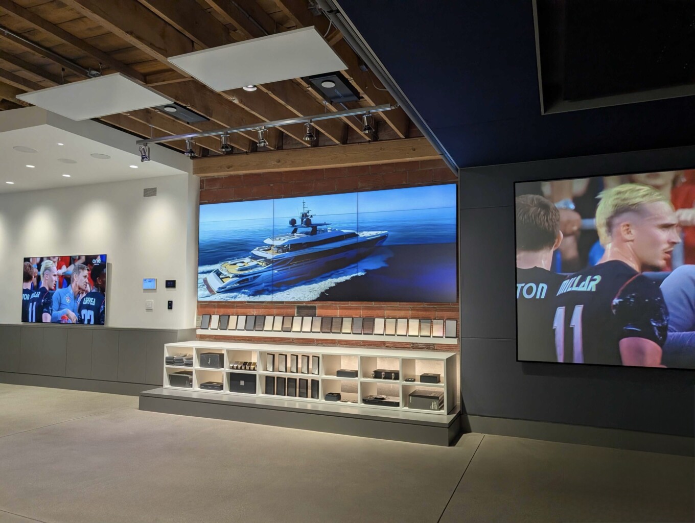 Sonance and James speakers on display in the Pure Image Yaletown showroom, with a large screen above the display shelving