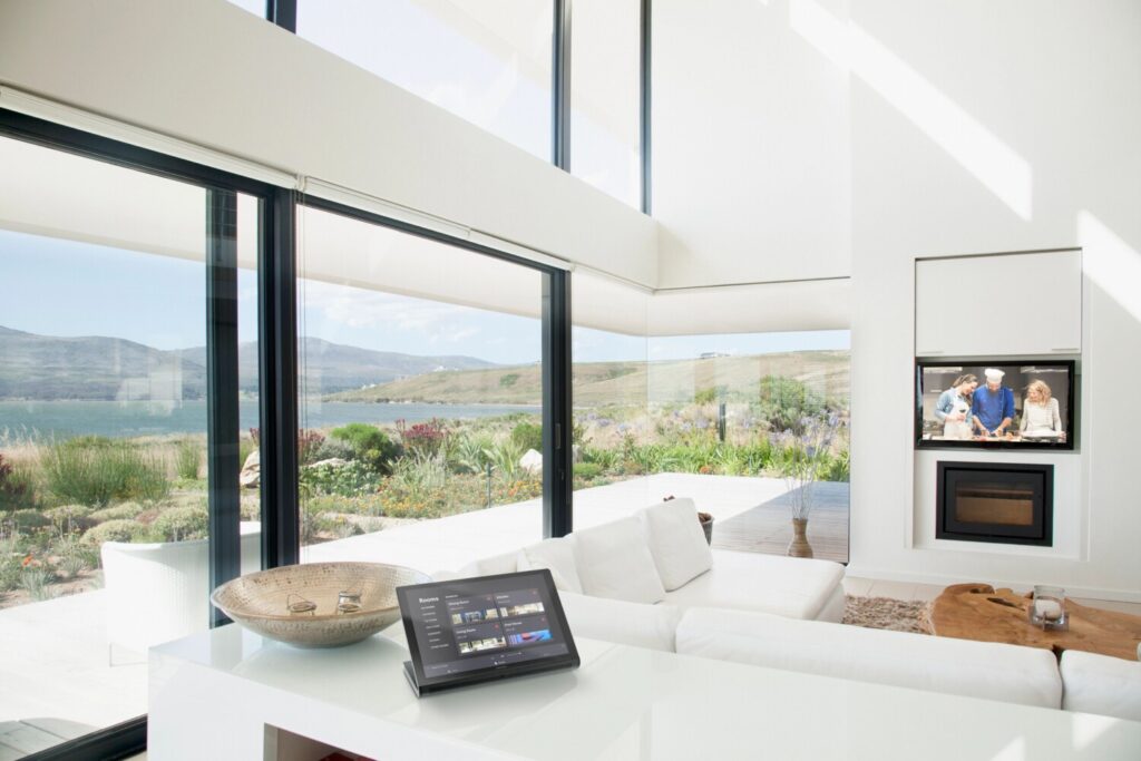 Crestron Home touchscreen control in luxury waterfront living room with motorized roller shades and integrated TV — smart home automation system installed by Pure Image Vancouver BC