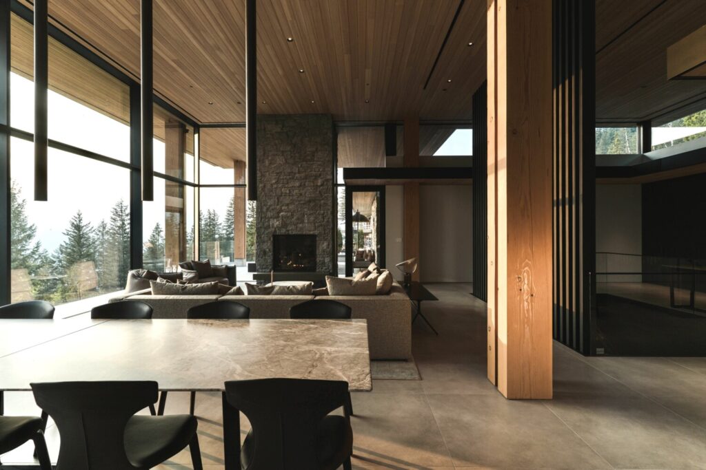 Luxury mountain home open plan living room with floor-to-ceiling windows, stone fireplace, wood ceiling and smart home automation — Pure Image luxury residential installation Calgary AB