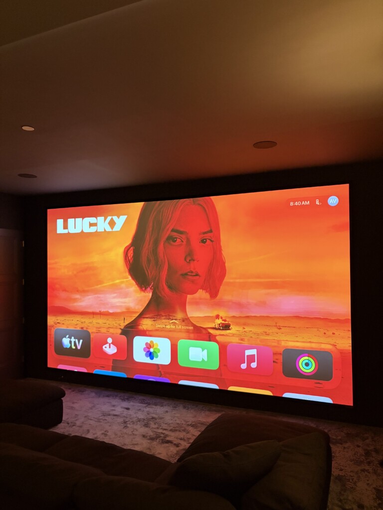 Custom home theatre with a large projection screen and integrated smart home control interface, installed by Pure Image.