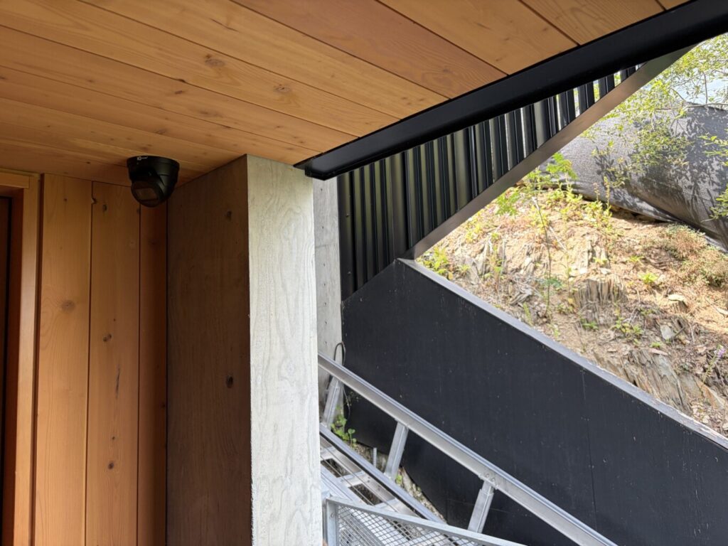 Discreet dome security camera mounted under the eaves of a modern home, installed by Pure Image for exterior surveillance.