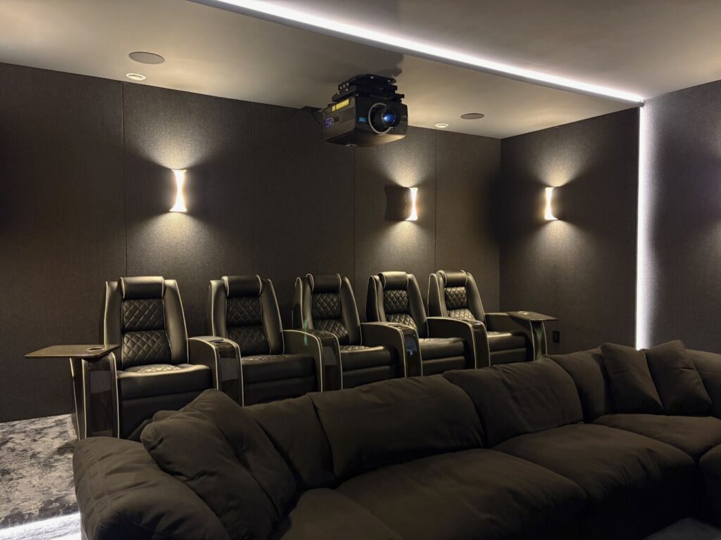 Home theatre with a ceiling-mounted projector, dark acoustic treatment and tiered leather seating in a luxury residence in Burnaby, BC