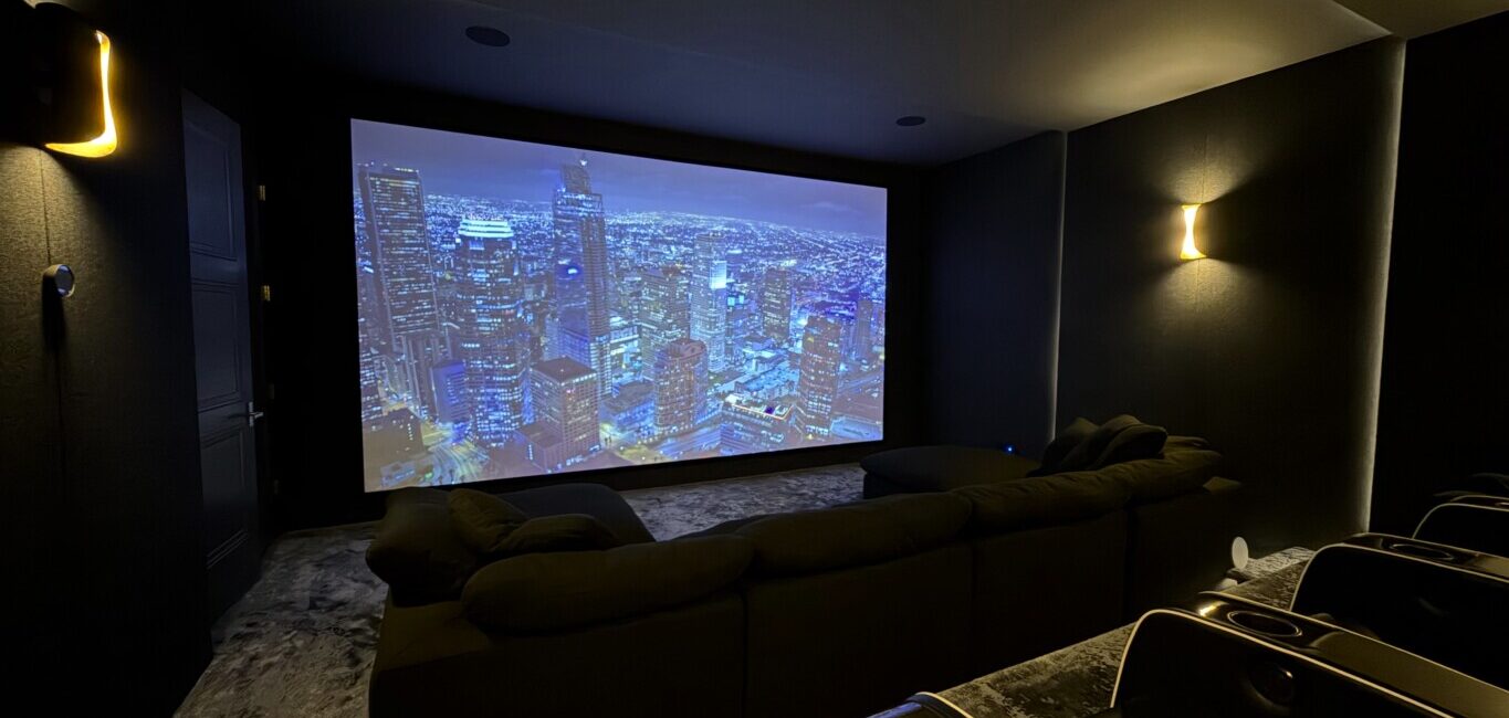 Immersive home theatre with a floor-to-ceiling projection screen and ambient wall lighting, custom built by Pure Image.