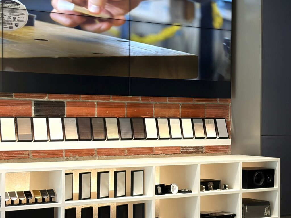 Lutron shade fabric swatches lining a brick wall above shelves of keypads, dimmers and recessed fixtures in the Pure Image Yaletown showroom