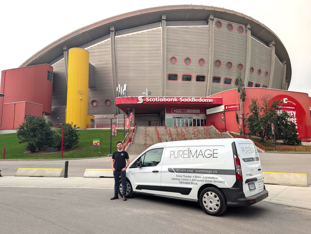 Pure Image Territory Manager Brendan with a Pure Image Van in front of a Scotiabank Saddledome in Calgary, Alberta.