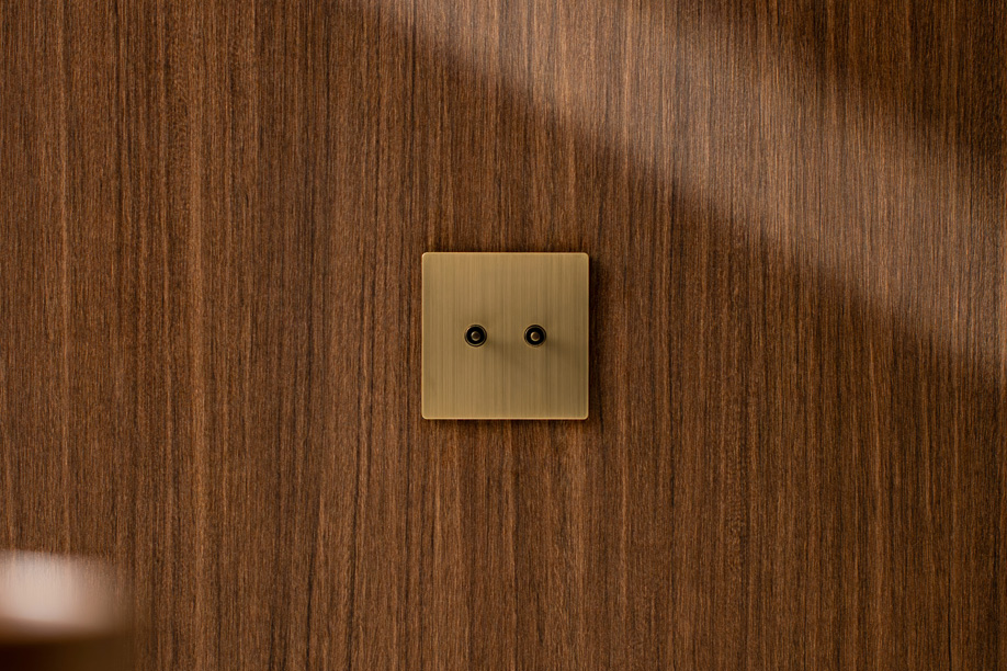 Two-button brushed brass Aviena keypad set flush in walnut panelling