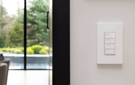 White Sunnata RF keypad mounted beside a glass door overlooking a garden